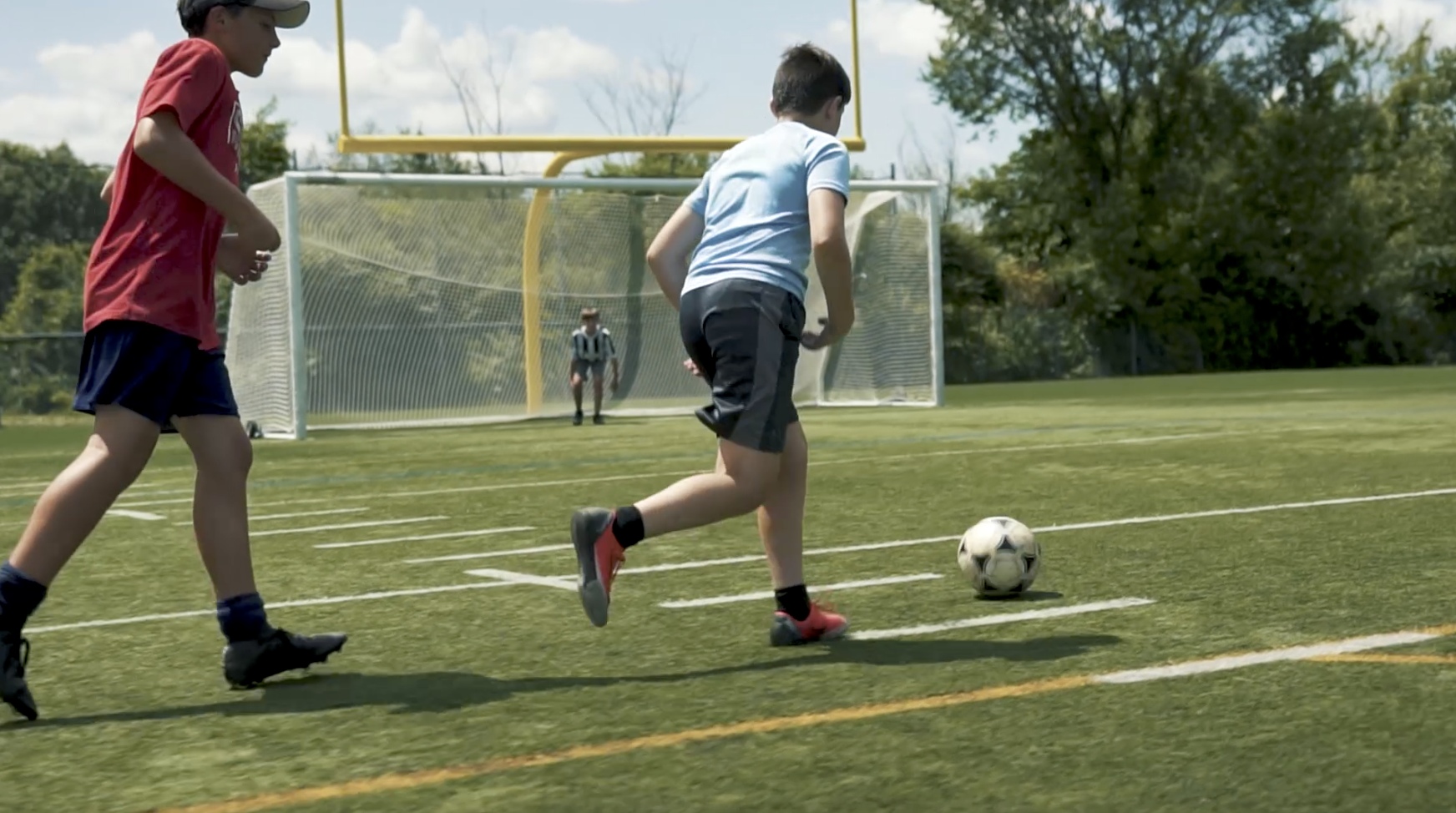 Enfants jouant soccer terrain extérieur